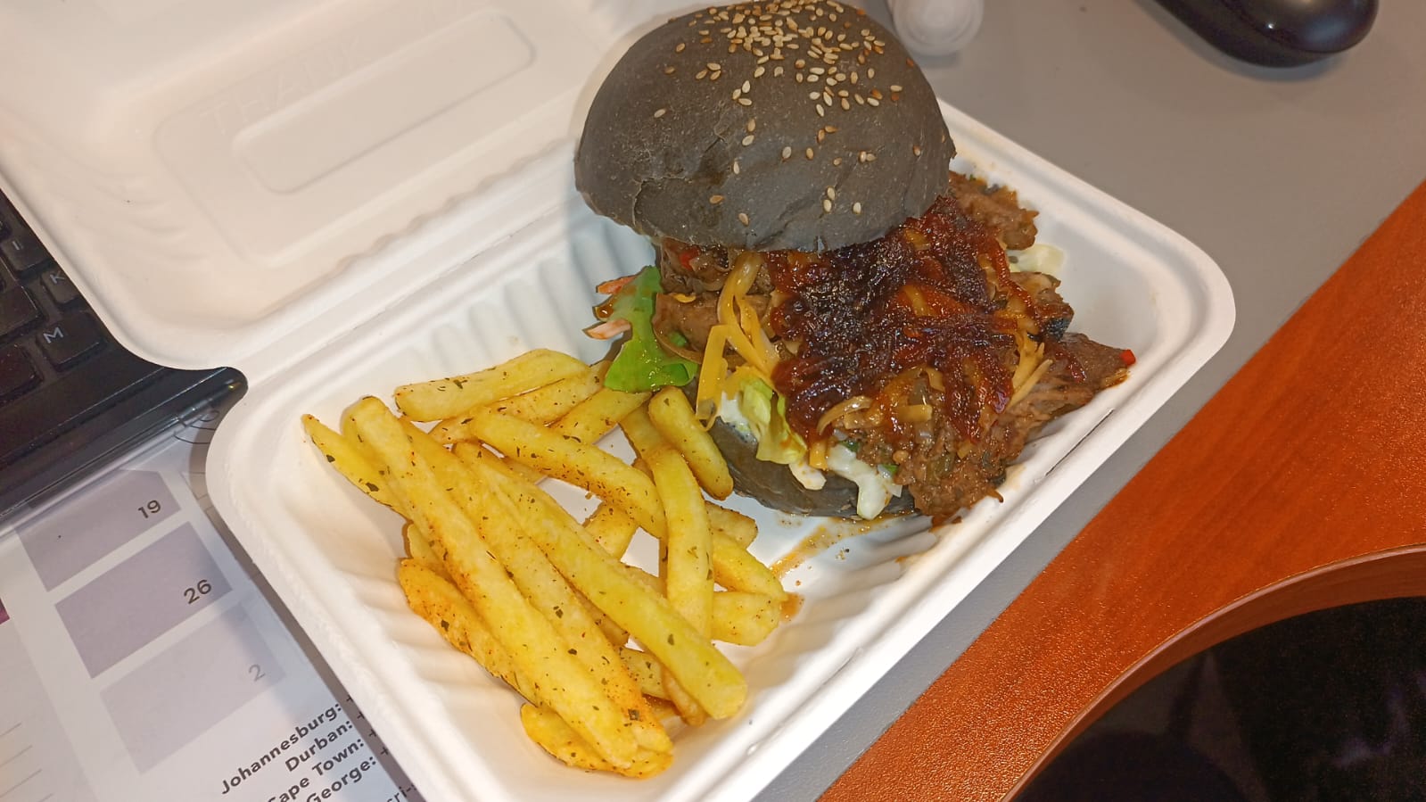 A burger with chips packed in a takeaway box