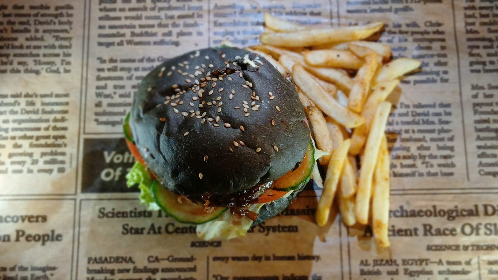 Overhead view of a black-bun burger with chips on the side