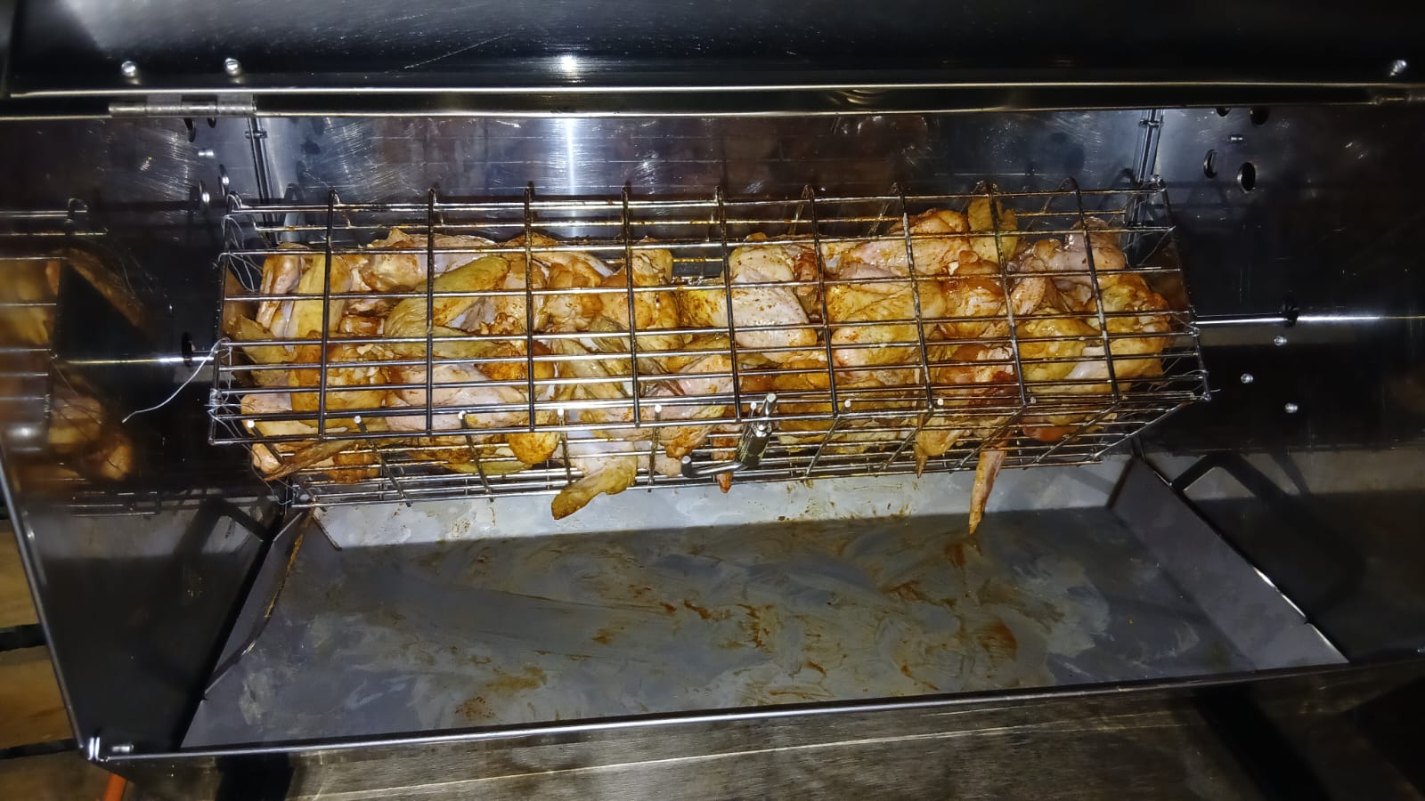 Chicken wings roasting in a rotating basket on the spit